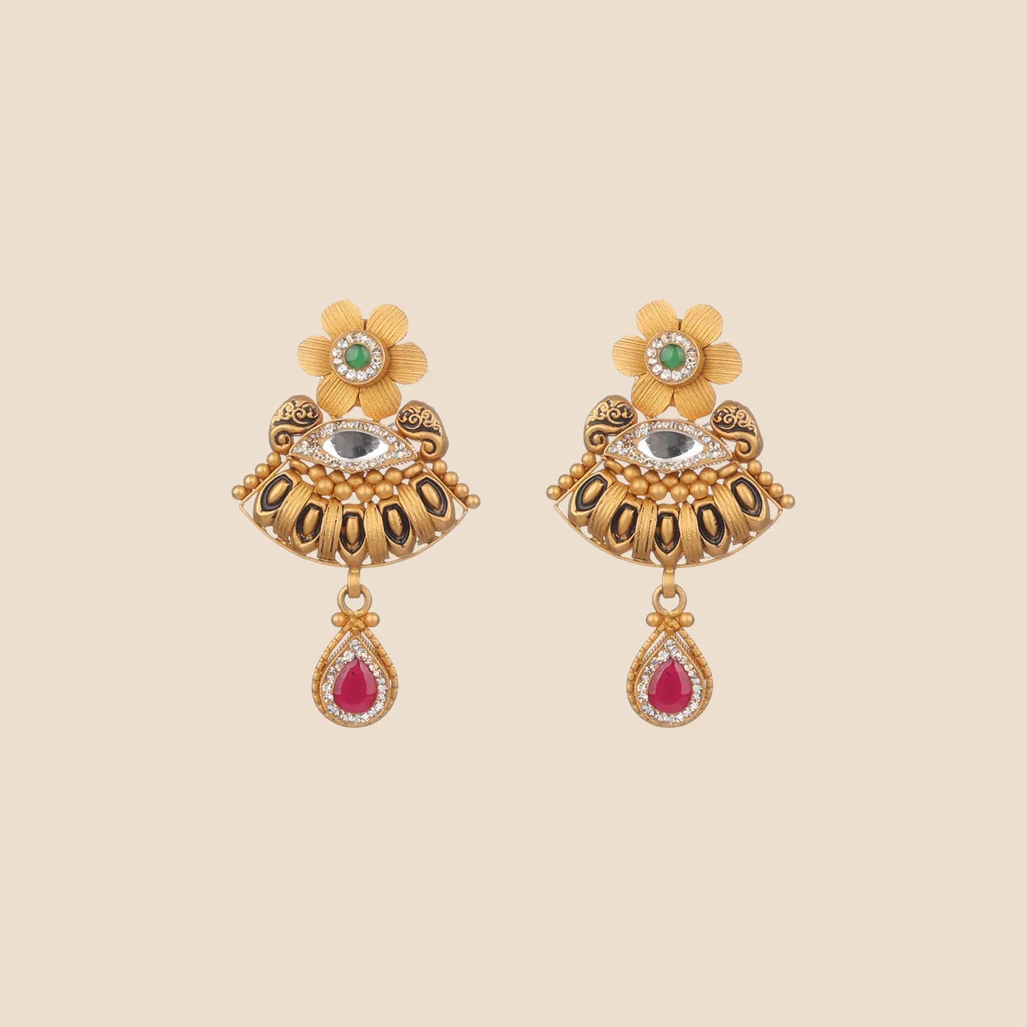 Gold dangle earrings featuring a floral stud with a central green stone, a semi-circular middle section with a horizontal clear stone and dark antiqued detailing, and a red teardrop stone dangle.