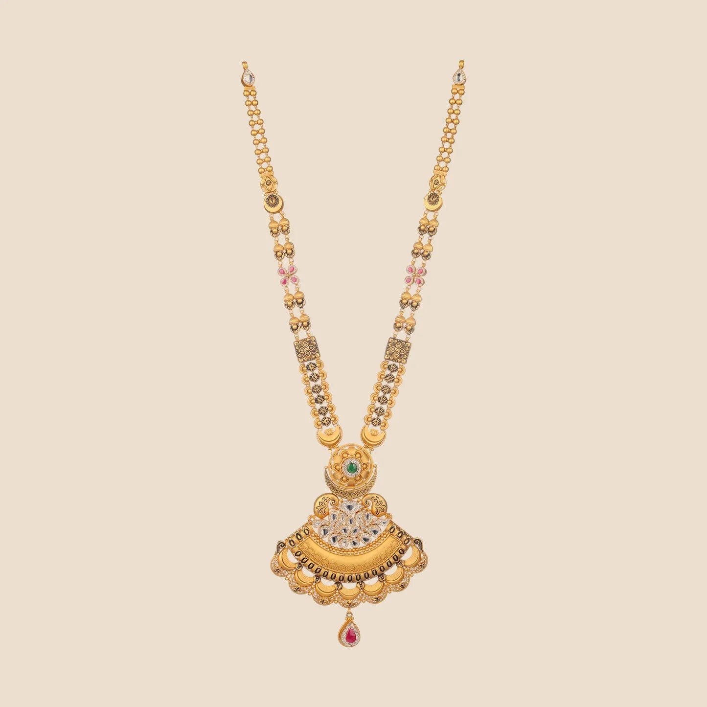 Long traditional gold necklace featuring a beaded double chain with interspersed motifs and a large, fan-shaped pendant detailed with a green stone top, clear stone clusters, and a single red teardrop dangle.