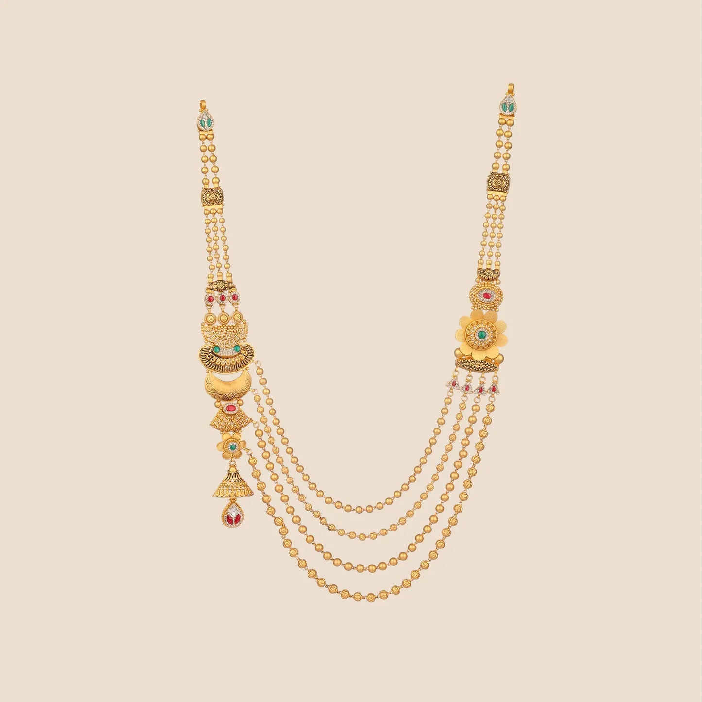 Long layered gold necklace featuring four draped beaded chains and ornate asymmetrical side pendants with floral and crescent motifs accented with red and green stones.