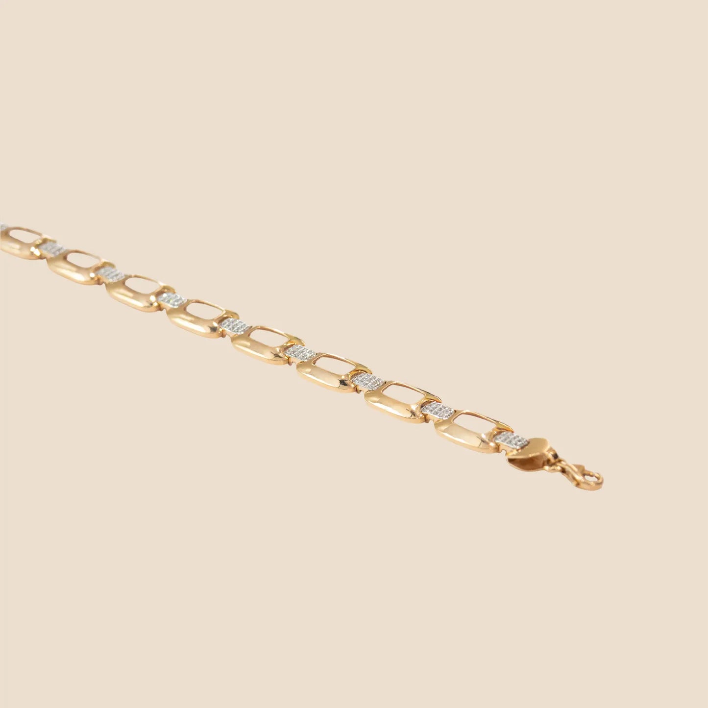 Gold bracelet with diamond accents on a beige background