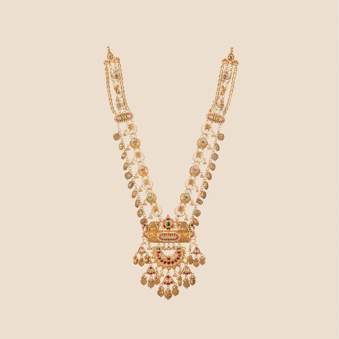 Long tiered gold necklace featuring intricate chain links, circular motifs, and a large statement pendant detailed with elephant figures, red stones, pearls, and cascading gold drops.