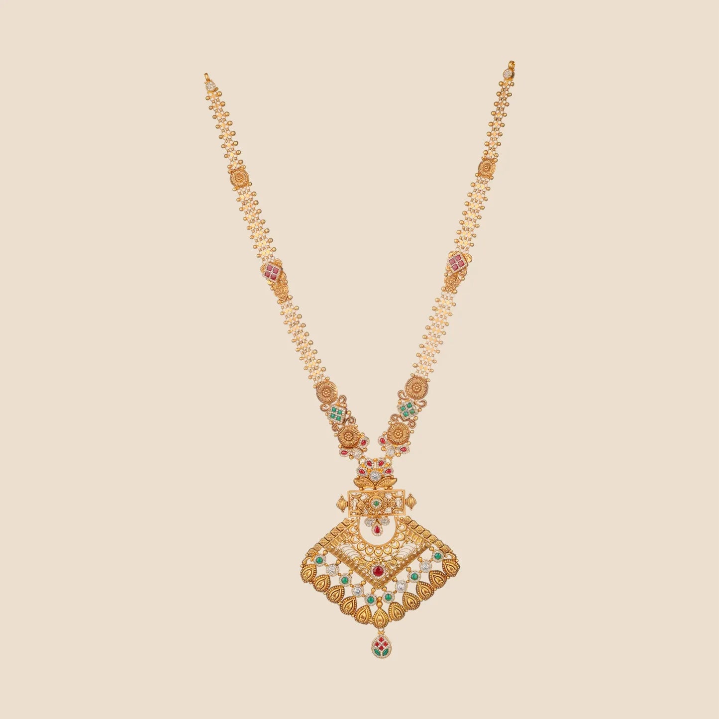 Long traditional gold necklace featuring an intricate chain interspersed with red and green stone motifs, leading to a large diamond-shaped geometric pendant adorned with clear, red, and green stones.