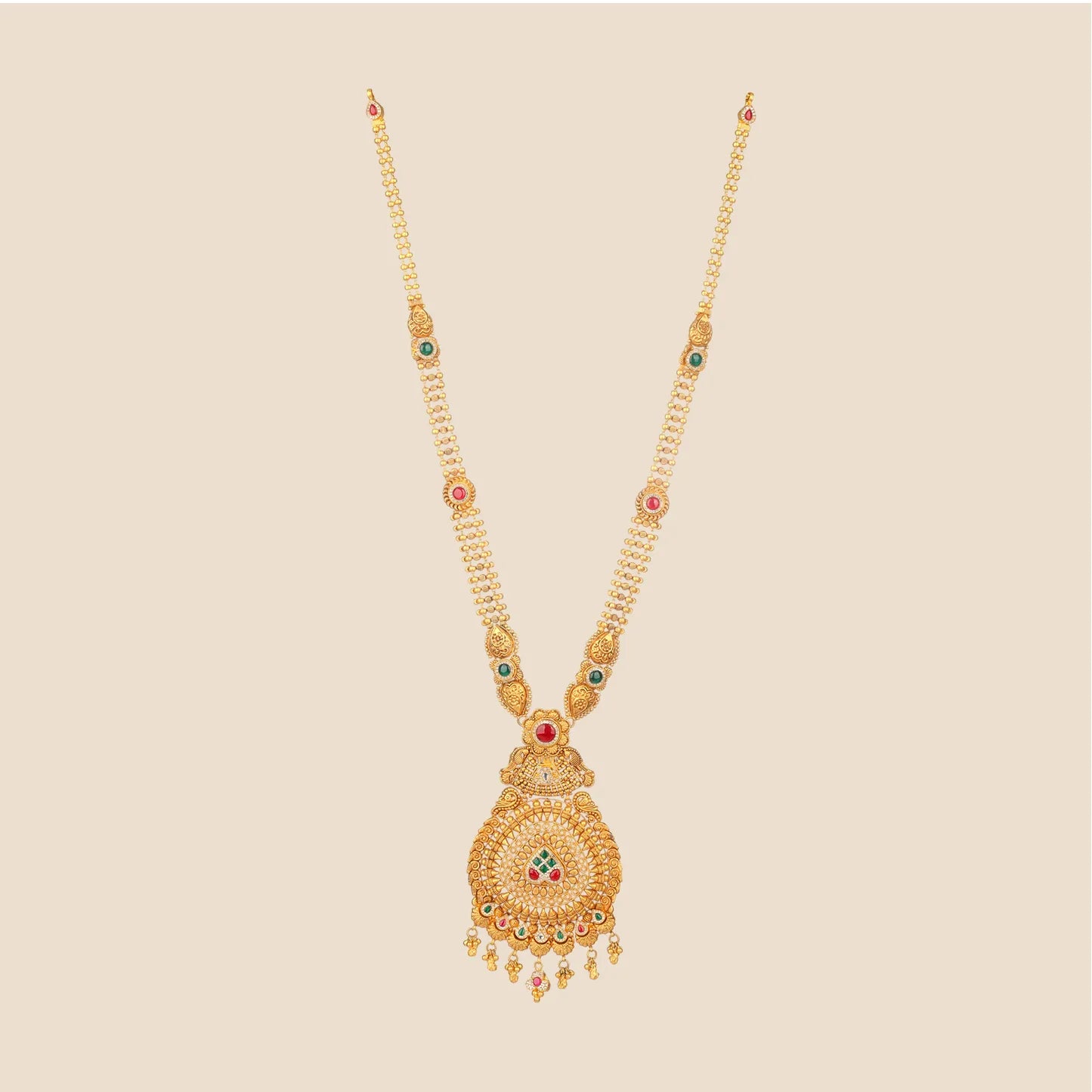 Long traditional gold necklace with a beaded chain featuring interspersed stone motifs, leading to a large, intricate filigree pendant accented with red and green stones and gold drops.