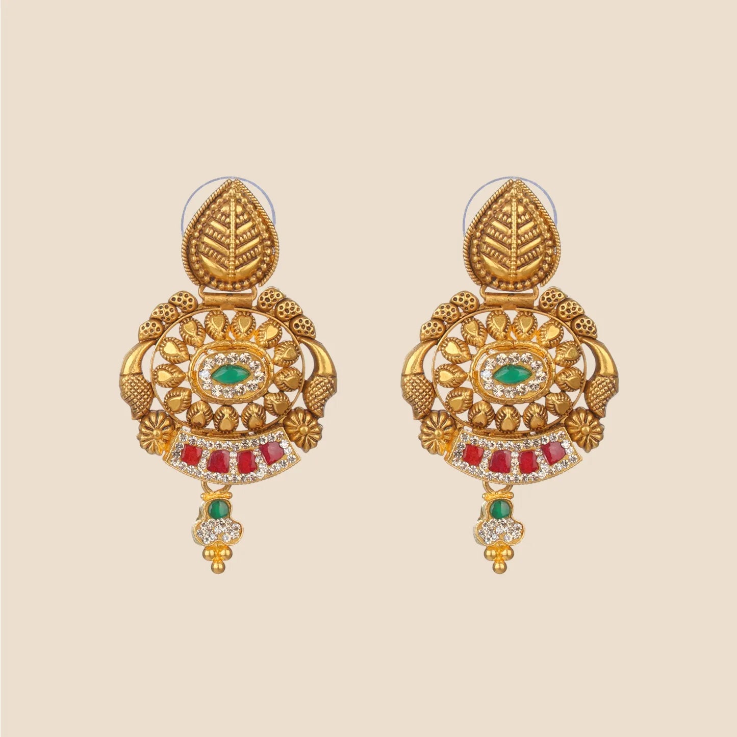 Ornate gold dangle earrings featuring a leaf-shaped top, a circular filigree center with a green stone, and red stone accents.