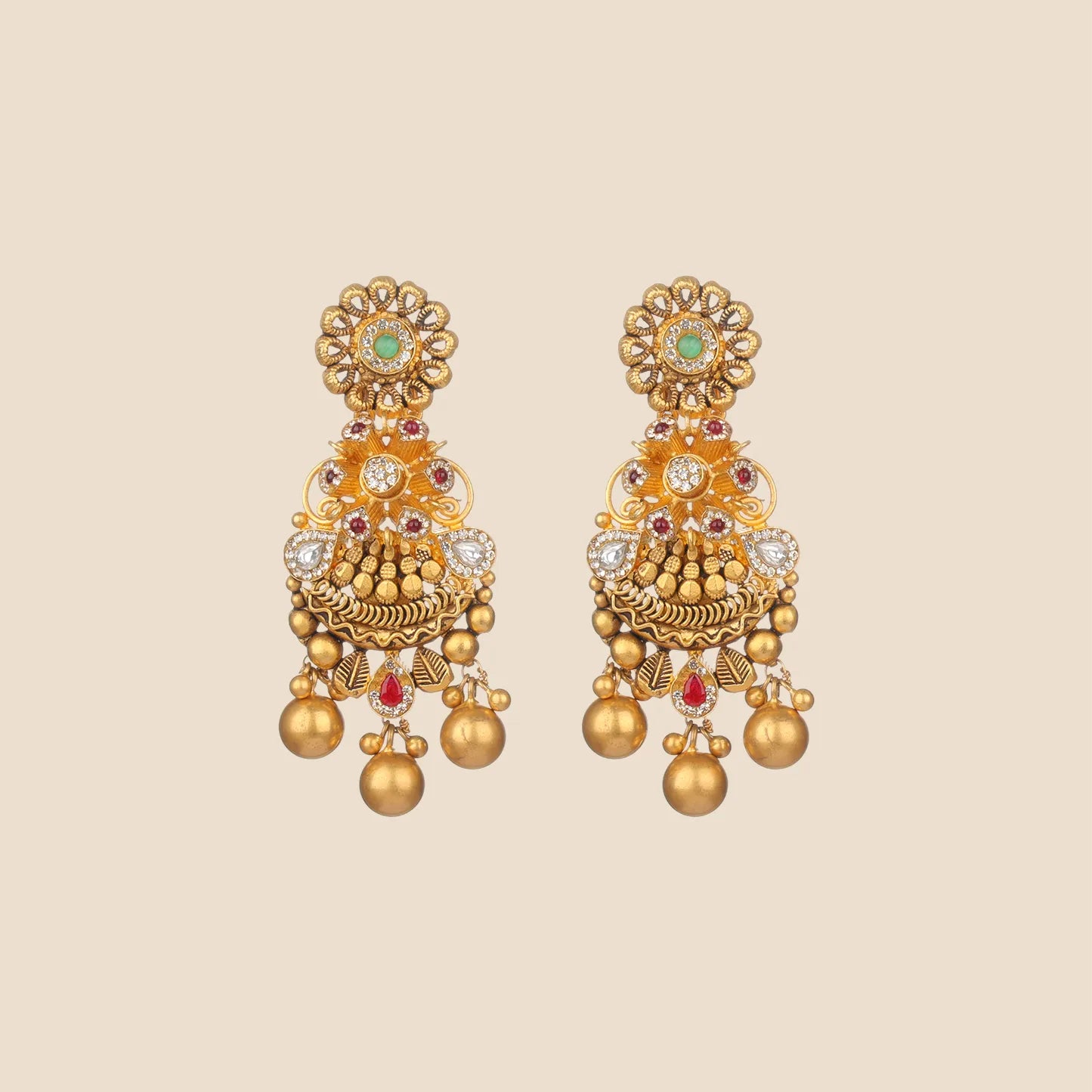 Ornate gold dangle earrings featuring a floral top with a green center stone, intricate filigree, red and clear stone accents, and hanging gold spheres.