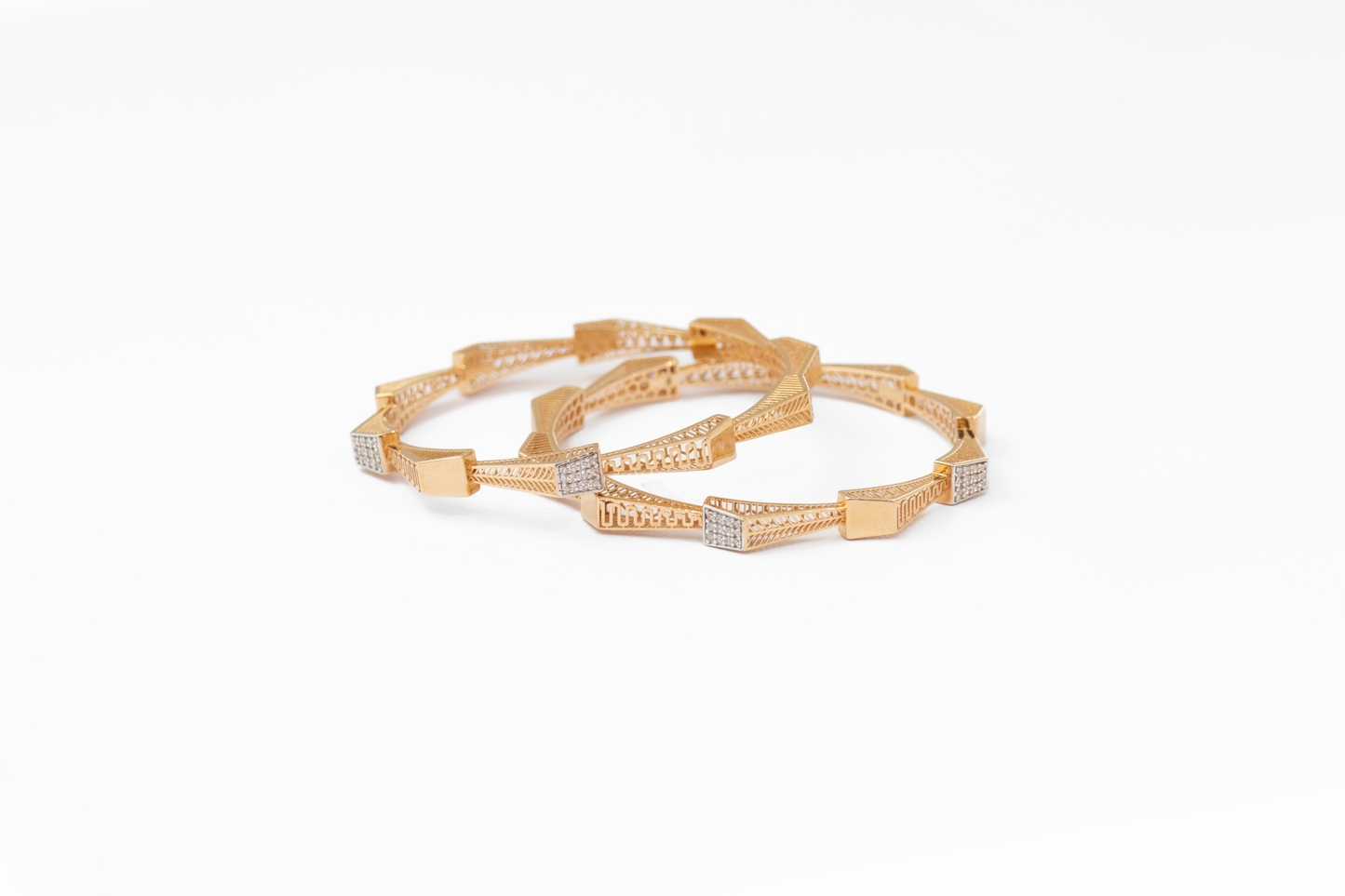 Gold bangles with diamond accents on a white background