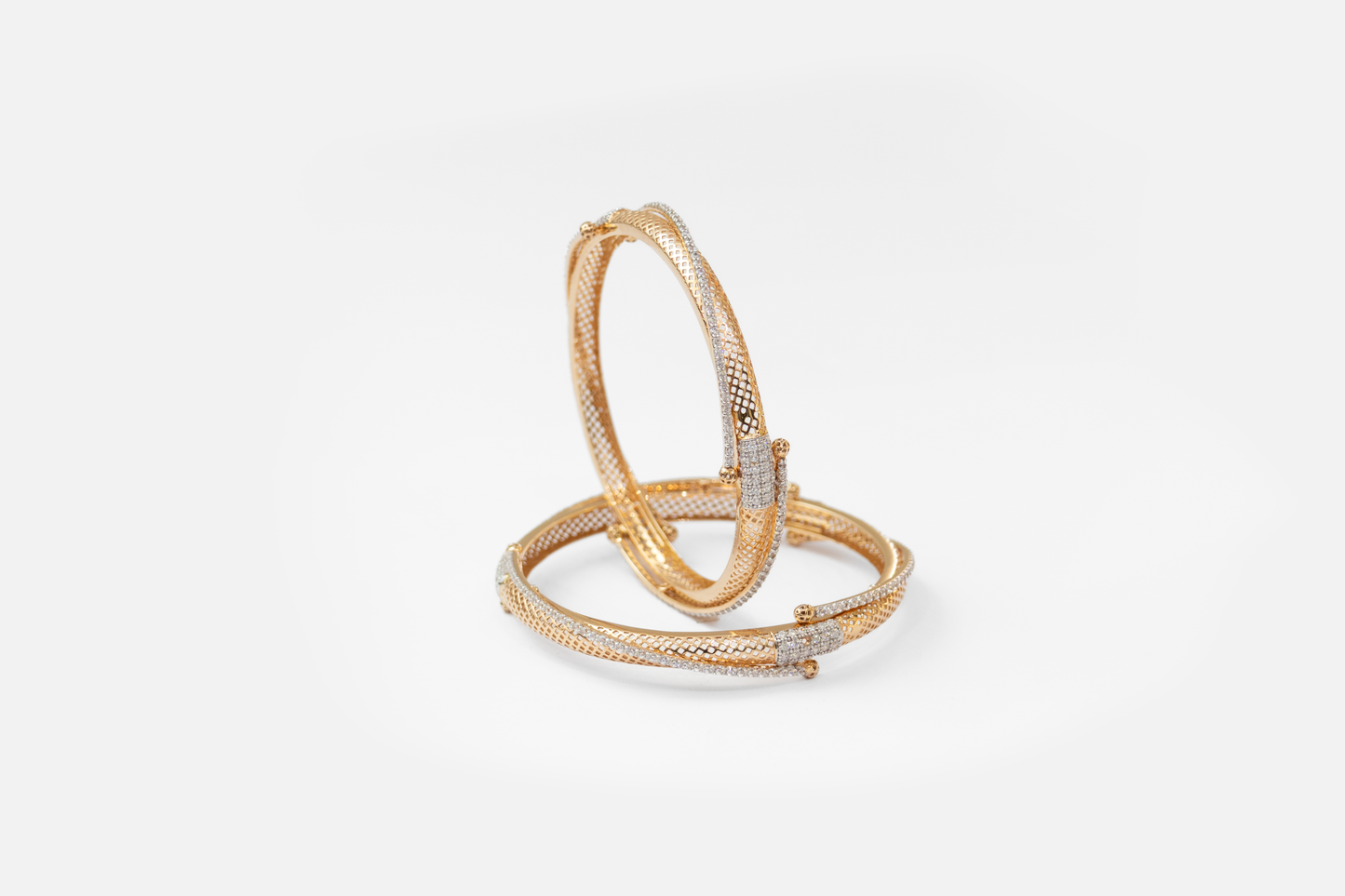 Gold bangles with diamond accents on a white background