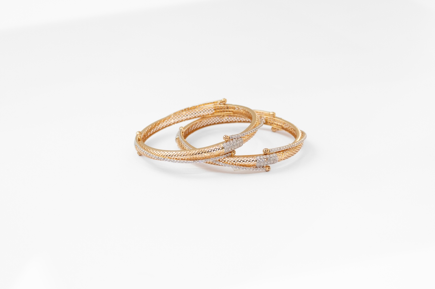 Two gold bangles with diamond accents on a white background
