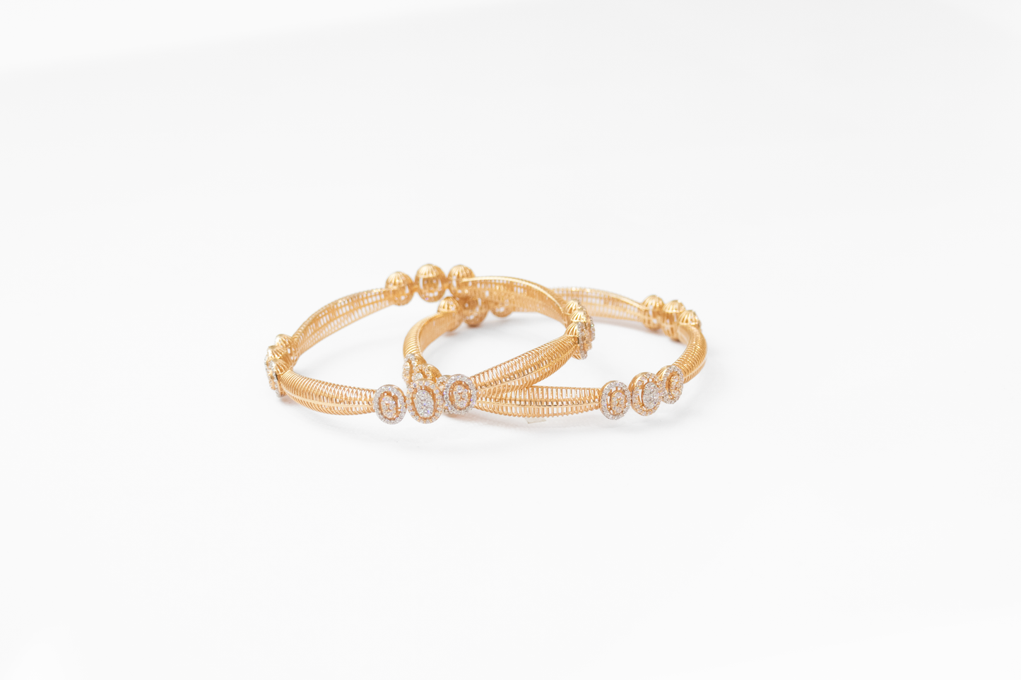 Two gold bangles on a white background