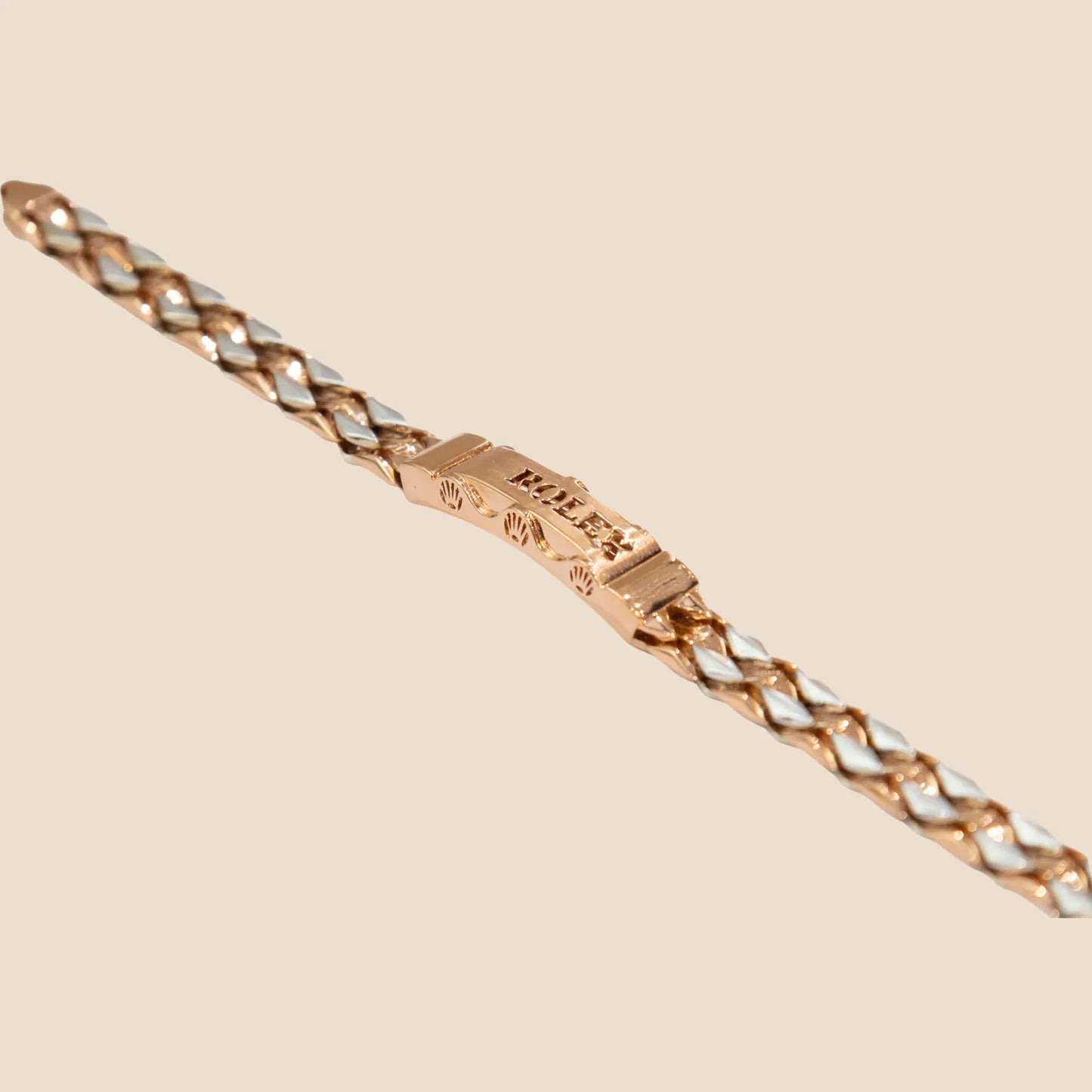 Rose gold chain bracelet with a clasp on a beige background