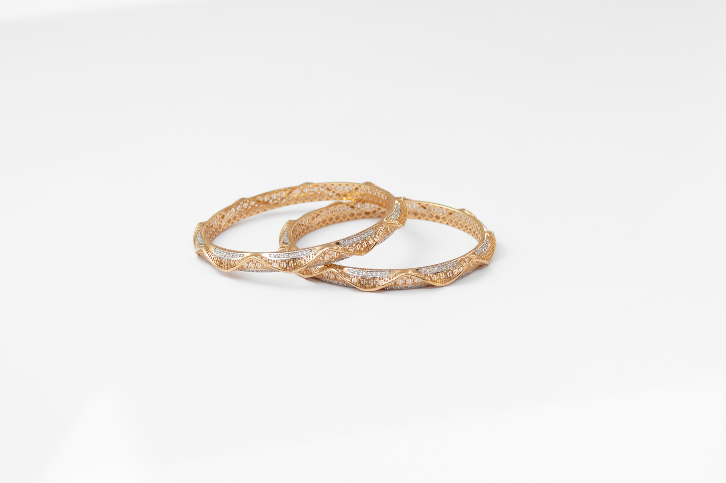 Two gold bangles on a white background