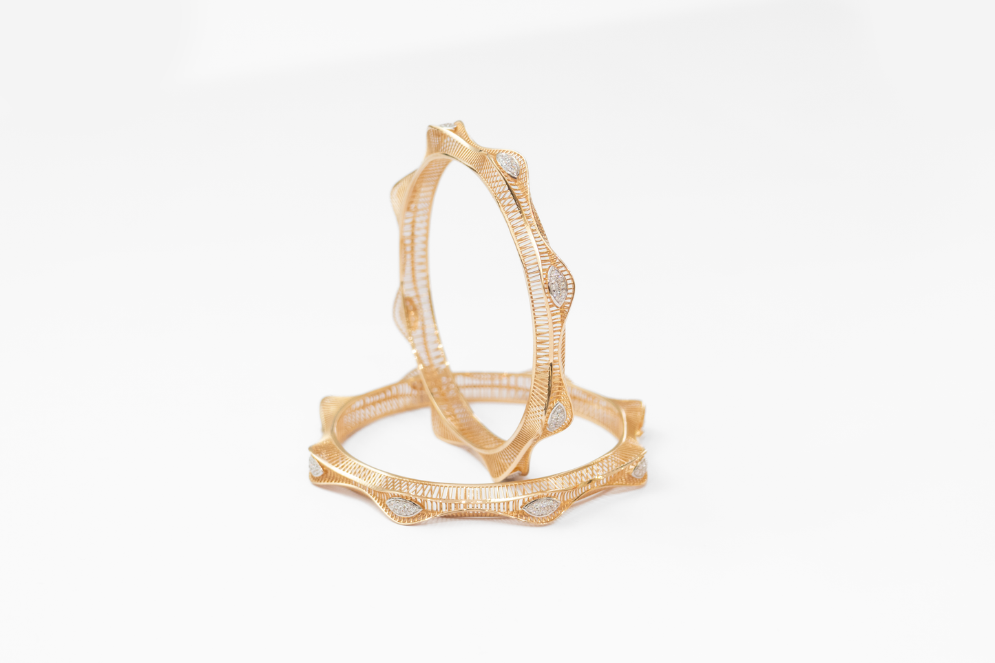 Gold bangles with intricate design on a white background