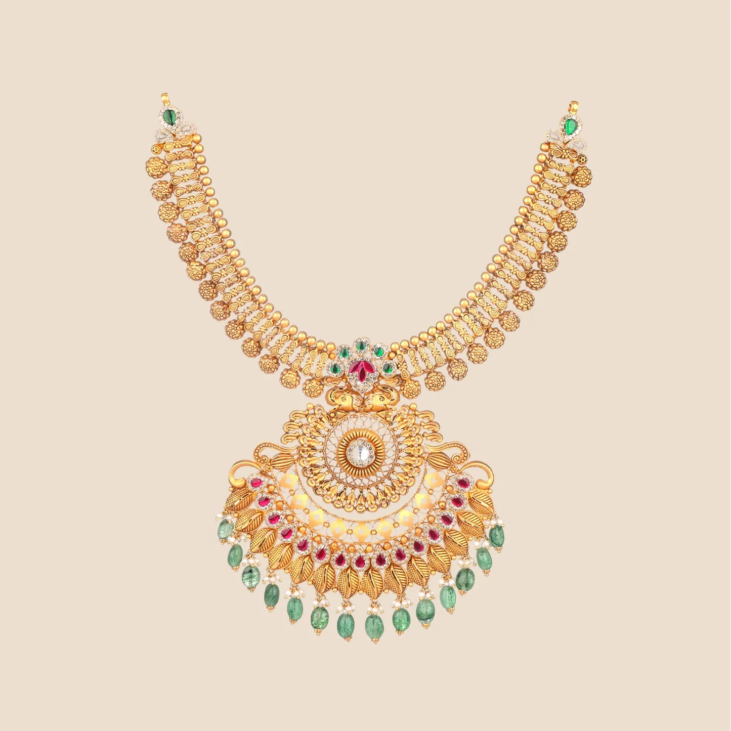 Detailed gold choker necklace featuring a broad textured band and a large, intricate pendant with a central clear stone, leaf motifs, red stone accents, and a cascading fringe of dangling green beads and small pearls.