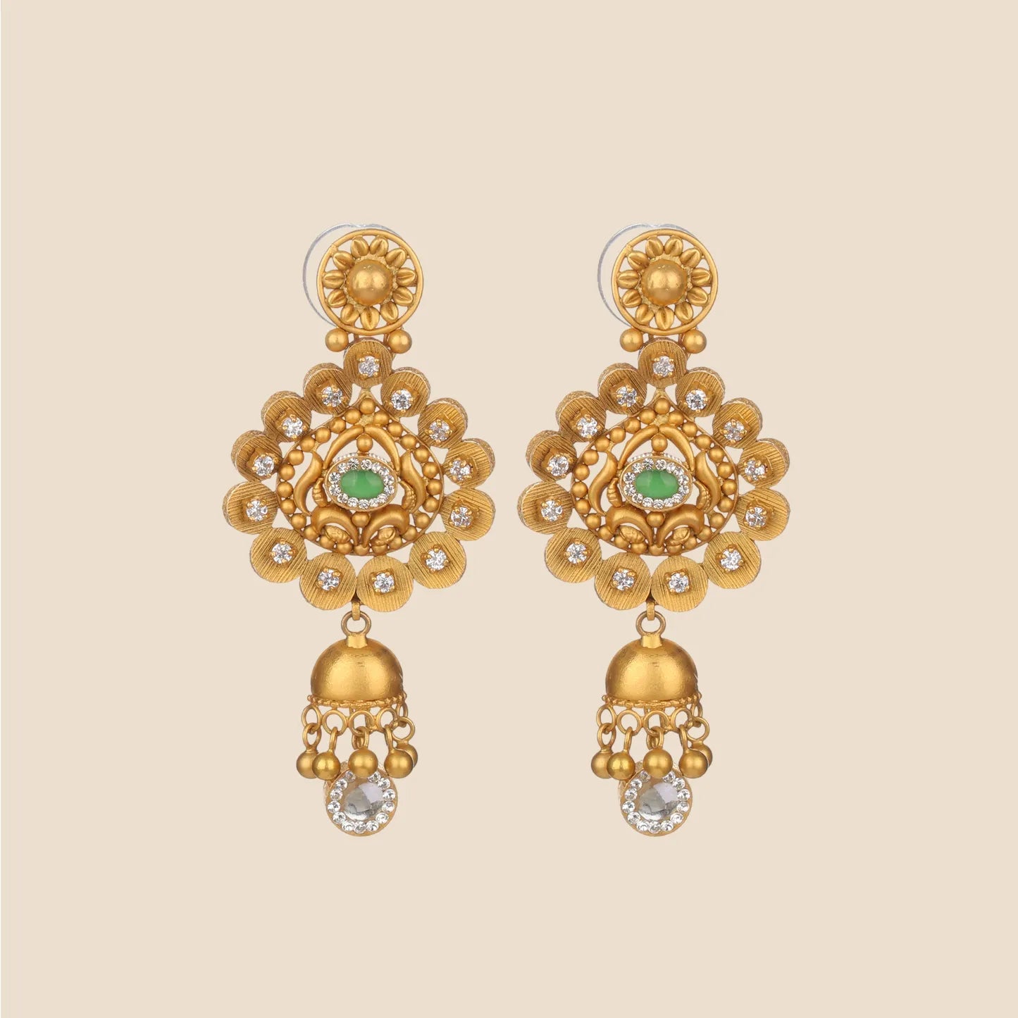 Gold jhumka earrings featuring an ornate sunburst circular motif with a central green stone, clear stone accents, and hanging gold bells.