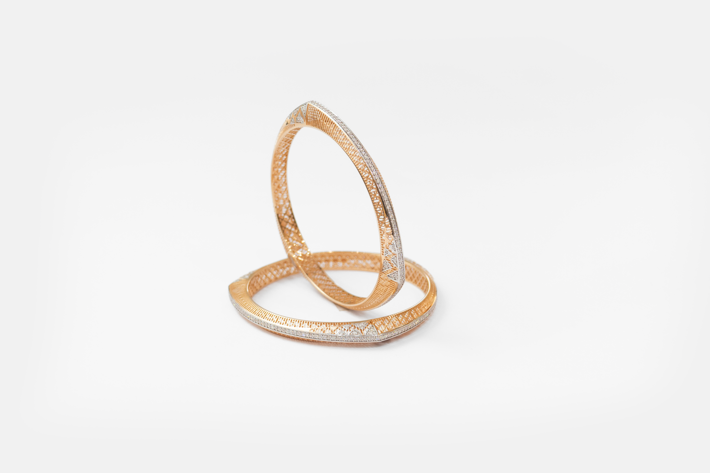 Gold bangles with intricate design on a white background