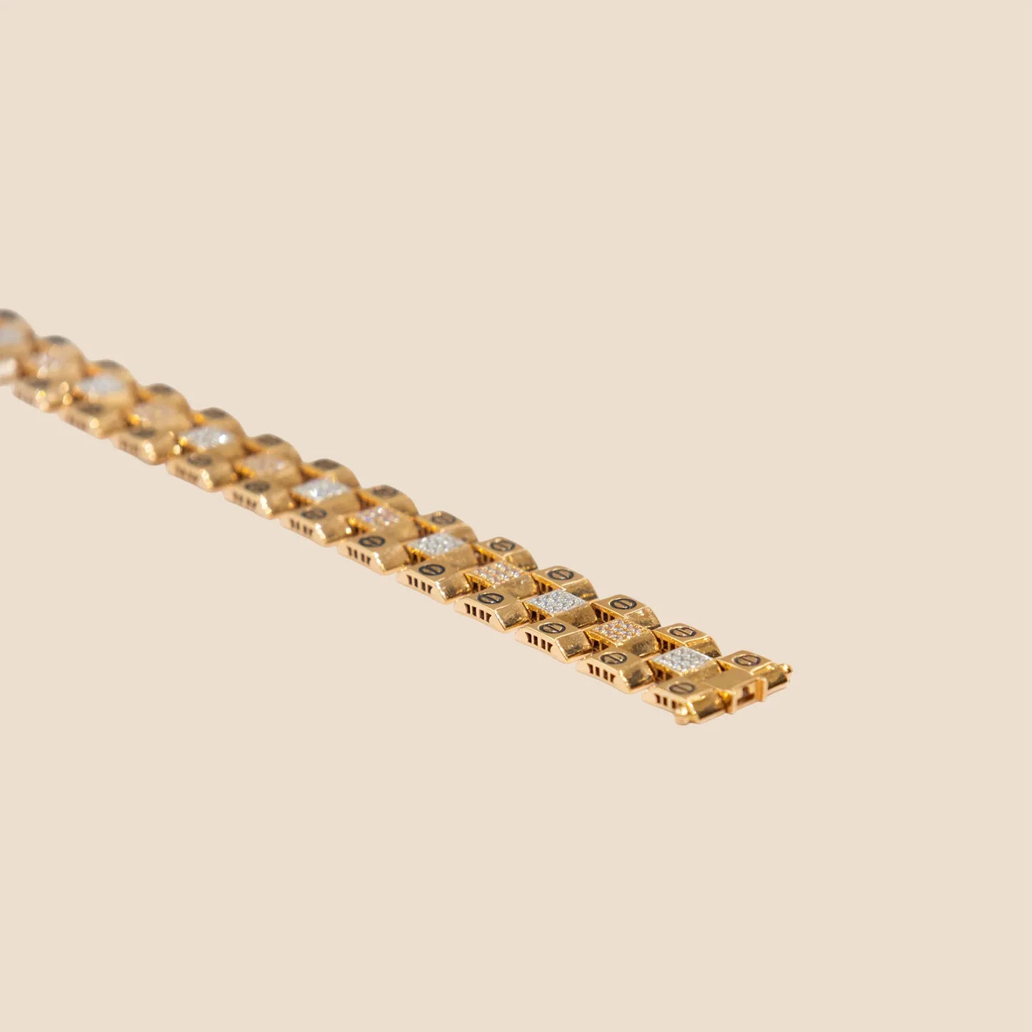 Gold bracelet with embedded stones on a beige background