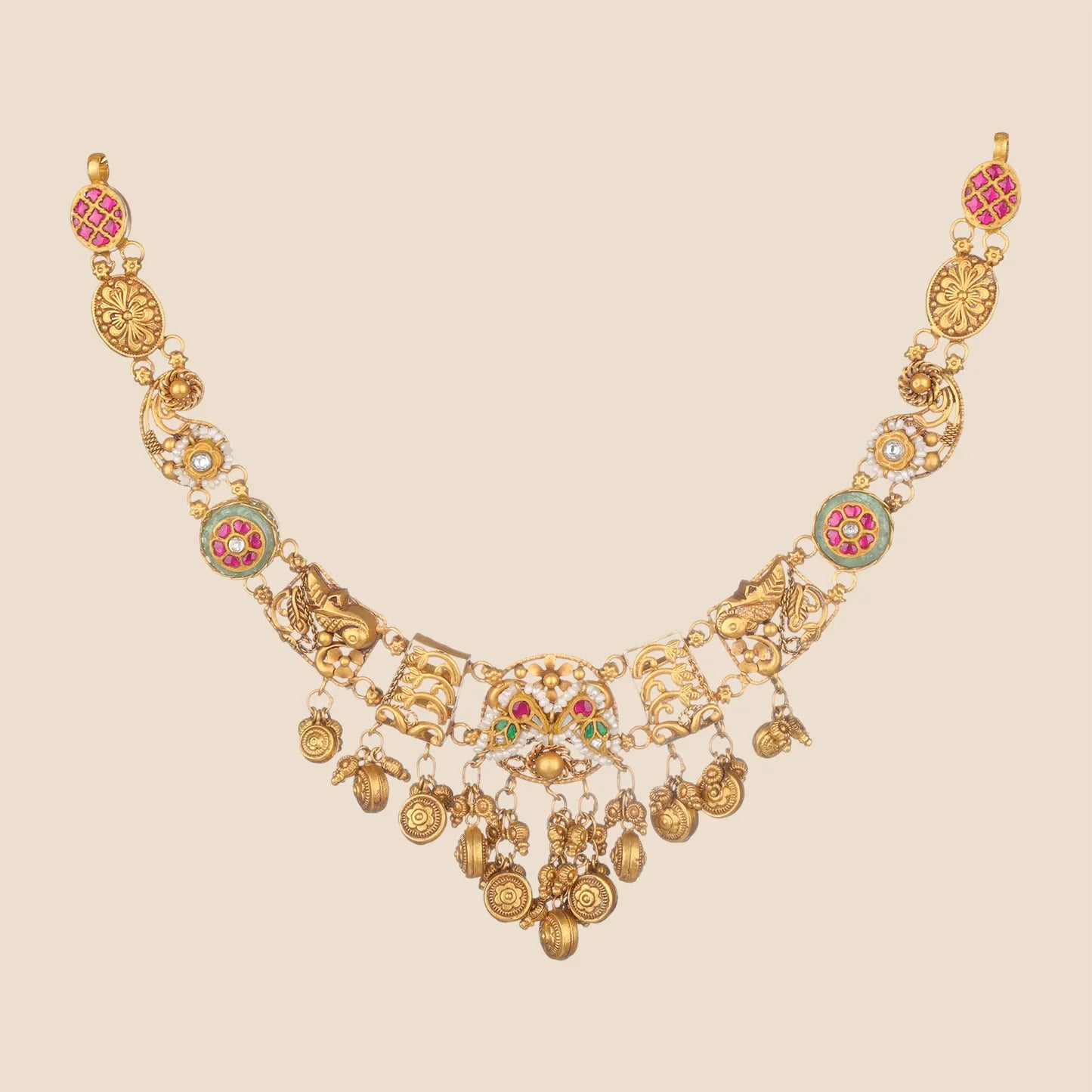 Traditional gold choker necklace featuring a chain detailed with pink stone and light green floral motifs, leading to a central peacock-inspired pendant adorned with pink and green stones and dangling textured gold coin charms.