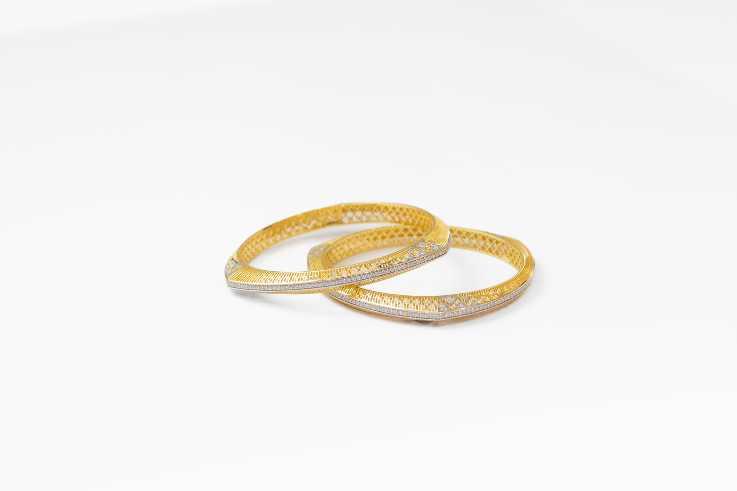 Two gold bangles on a white background